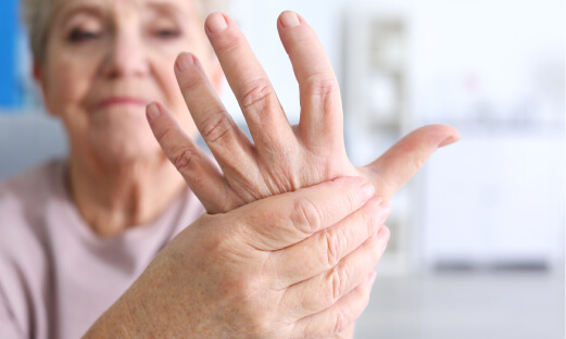 Elderly woman experiencing discomfort in her hand.