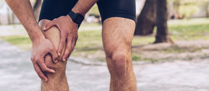 Man cartilage tear holding sore knee