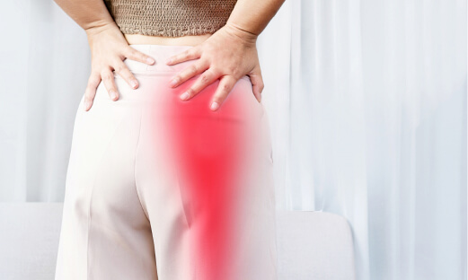 Woman holding her hips as pain radiates down her leg.
