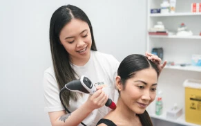 Woman receiving shockwave therapy on her shoulder.